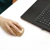 A hand is using a wooden computer mouse next to a laptop. Produktbild-Vorschau