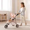 A young girl is pushing a doll stroller with a doll inside, in a room with a window and furniture. Náhľad obrázku produktu