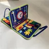 A blue fabric busy board for children, laid open on a white surface. Produktbild-Vorschau