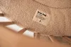 A close-up of a beige, fluffy, round playpen mat with a tag that reads 'Bear hug'. Produktbild-Vorschau