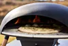 A pizza is being cooked in an outdoor pizza oven. Produktbild-Vorschau