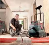 A man is using a vacuum cleaner in a construction or renovation site. Produktbild-Vorschau