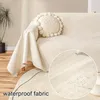 A close-up view of a cream-colored sofa with a waterproof fabric cover, showing water beading on the surface. Produktbild-Vorschau