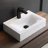 A white ceramic sink with a black faucet is placed on a wooden countertop. Produktbild-Vorschau