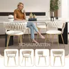 A woman sits at a dining table with chairs, holding a cup. Produktbild-Vorschau