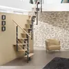 A modern staircase with a wooden finish and metal railings is shown in a well-lit room with a stone wall and a beige armchair. Produktbild-Vorschau