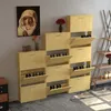 A collection of light wood shoe cabinets with multiple flip-down compartments, arranged against a light gray wall. A painting of the Virgin Mary hangs on the wall above one of the cabinets. A small vase with flowers sits on top of another cabinet. Podgląd zdjęcia produktu