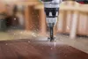 A close-up shot of a Bosch drill bit drilling into a wooden surface, creating sawdust. Voir les images du produit