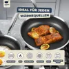A close-up of two cooked salmon fillets in a honeycomb-patterned frying pan, garnished with lemon slices, with other cookware and kitchen elements visible in the background. Produktbild-Vorschau