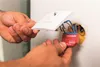 Hands installing a smart switch into a wall socket. Produktbild-Vorschau