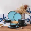 Das Geschirrset steht auf dem Tisch, umgeben von Geschenkboxen mit blauen Bändern, und Blumen. Voir les images du produit