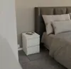 A white nightstand with two drawers next to a bed. Anteprima dell’immagine prodotto