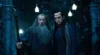 Two men, one older with a long beard and the other younger with dark hair, stand in a dimly lit, ornate outdoor setting with glowing lights above. Podgląd zdjęcia produktu