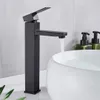 A black faucet is shown in a bathroom setting, with water flowing into a white sink. Two soap dispensers are visible in the background. Náhľad obrázku produktu
