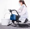 A person wearing protective gear is using a paint sprayer connected to a bucket. Anteprima dell’immagine prodotto
