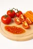 A wooden cutting board with tomatoes, carrots, and tomato sauce. Anteprima dell’immagine prodotto