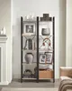 A tall, multi-shelf bookcase with various decorative items and books, placed in a room setting next to a fireplace. Náhľad obrázku produktu