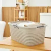 A laundry basket filled with folded towels sits on a wooden surface in a bathroom setting. Produktbild-Vorschau