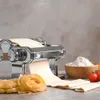 A pasta machine with dough being processed, along with uncooked pasta, flour, and tomatoes. Náhľad obrázku produktu