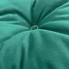 A close-up view of a tufted green cushion, showing the texture of the fabric and the button detail. Produktbild-Vorschau