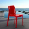 A red chair is placed on a patio next to an infinity pool with the ocean in the background. Produktbild-Vorschau