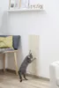 A cat is scratching a sisal board mounted on a white wall, next to a chair with a yellow cushion. Produktbild-Vorschau