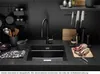 A modern black kitchen sink area with a faucet, knives on a magnetic strip, cutting boards, and vegetables. Podgląd zdjęcia produktu