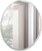 A round mirror reflecting a window with wooden blinds and trees outside.