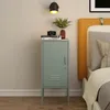 A mint green nightstand with a closed door and a small vent detail is placed next to a bed with an orange headboard. Books, a camera, and a vase with greenery are on top of the nightstand. Anteprima dell’immagine prodotto