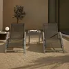 Two lounge chairs and a small table are set up on a gravel patio next to a building. Voir les images du produit