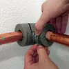 Hands are shown installing pipe insulation on copper pipes. Produktbild-Vorschau