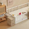 A child's bed with safety rails and a stuffed toy on it, next to a wooden cabinet with books. Anteprima dell’immagine prodotto