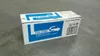 A cardboard box containing a toner cartridge is placed on a concrete floor. Voir les images du produit