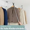 A hand is using a telescopic pole with a hook to reach for a jacket on a high clothes rack. Produktbild-Vorschau