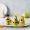 Three decorated pears on a plate, with a candle and another pear in the background. Podgląd zdjęcia produktu