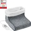 A close-up studio shot of a grey electric foot warmer with a white fluffy lining, placed on a white background. A white power cord with a controller is attached. Produktbild-Vorschau