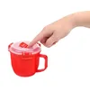 A hand is pressing down on the lid of a red microwave soup mug. Produktbild-Vorschau