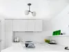 A modern, minimalist kitchen with white cabinets and a white countertop. Produktbild-Vorschau
