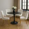 A dining set with a round black table and four cream-colored chairs with gold legs, arranged in a room. Náhľad obrázku produktu