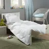 A child's bed with white bedding, a stuffed frog, and a small doll on the floor. Produktbild-Vorschau