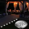 A patio area at night, illuminated by string lights and solar ground lights. Produktbild-Vorschau