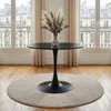 A round black dining table with a tulip base is placed on a beige rug in front of a large window with curtains. Produktbild-Vorschau