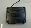 The back of a black DeWALT DCB107 battery charger is shown on a light gray surface. Produktbild-Vorschau
