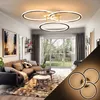 A modern living room with a sectional sofa, coffee tables, and a large window overlooking a garden. A contemporary ceiling light fixture is prominently displayed. Podgląd zdjęcia produktu