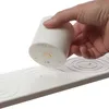 A hand is holding a white LED candle over a white strip with circular indentations. Produktbild-Vorschau