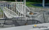 Two white Acapulco chairs and a small glass table with a cup of coffee and pastries on a patio. Produktbild-Vorschau