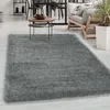 A shaggy gray rug is laid out in a living room setting, with a coffee table and furniture visible in the background. Produktbild-Vorschau