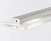 A close-up shot of a modern light fixture mounted on a clear glass shelf. Produktbild-Vorschau