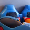 A close-up view of a blue children's bed designed to look like a race car, showing the headboard and part of the mattress and pillows. Anteprima dell’immagine prodotto