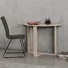 A green chair sits next to a light wood desk with a notebook and pens on it, against a concrete wall. Náhľad obrázku produktu